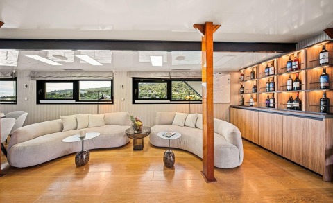 Karizma luxury yacht interior lounge with curved cream sofa, wood accents, and a well-stocked bar