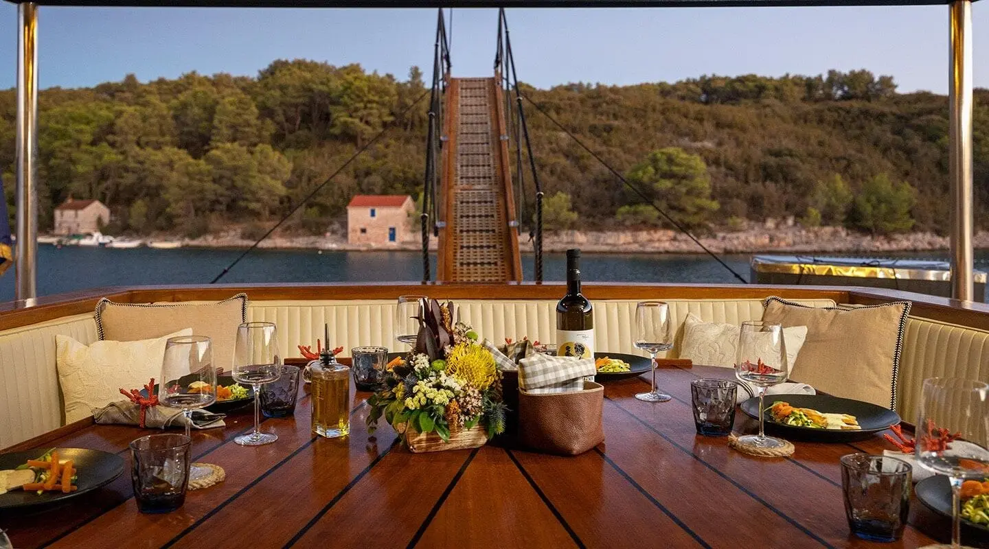 Sunset-lit luxury gulet yacht Aborda deck with wooden table set and flowers